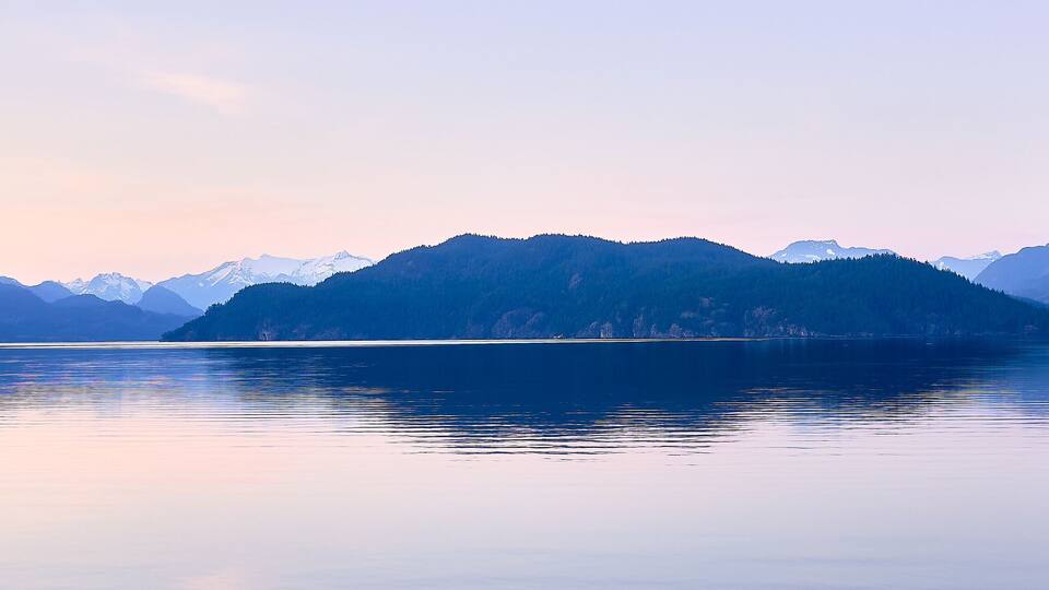 A calm lake surrounded by mountains with snow-capped peaks.