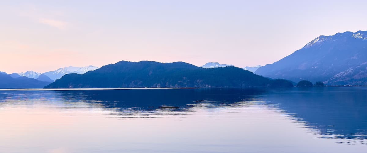 A calm lake surrounded by mountains with snow-capped peaks.