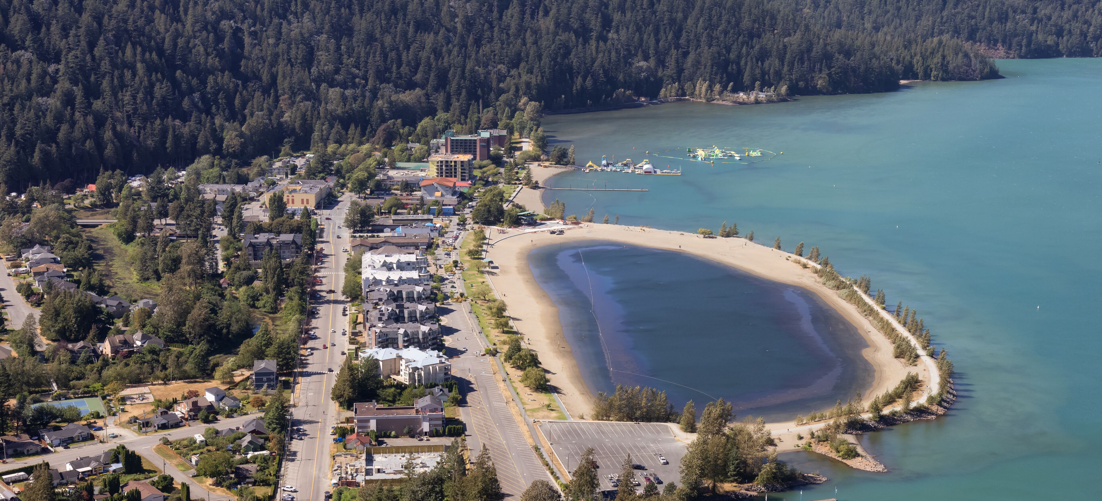 Small touristic town by the lake with Canadian Mountain Landscape. Sunny Summer Day. Harrison Hot Springs, British Columbia, Canada.