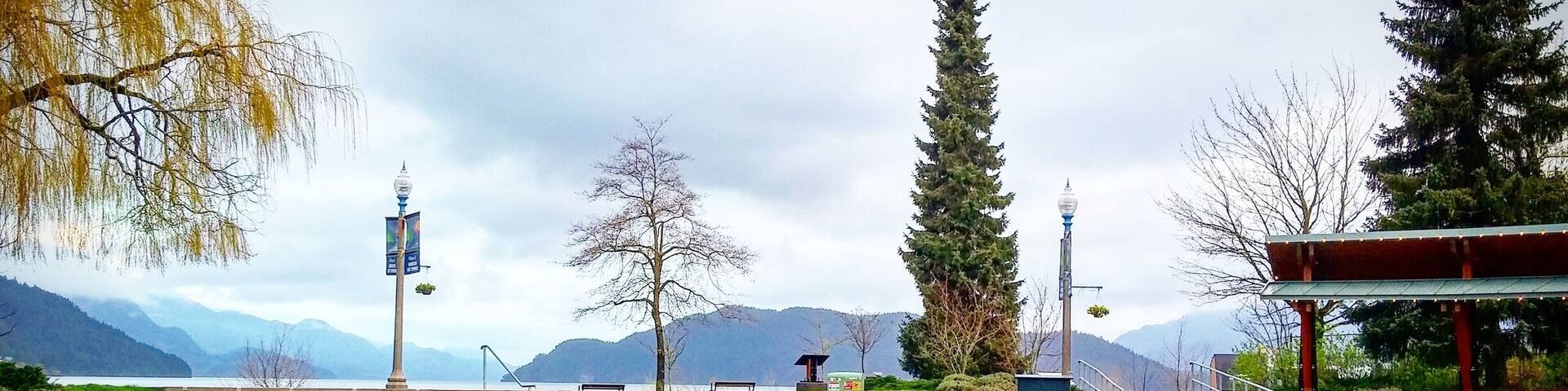 A park with a concrete pathway, benches, and a sign that reads "HARRISON LAKE".
