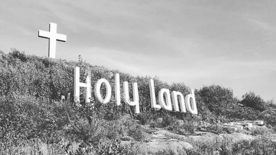 A cross and the words "Holy Land" on a hill.