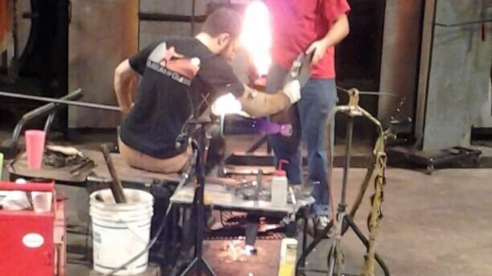 A workshop with welding equipment and a person welding a metal structure.