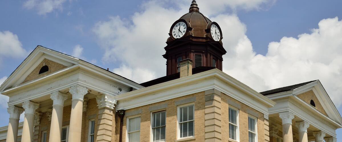 A historic building with a clock tower, columns, and a dome.
