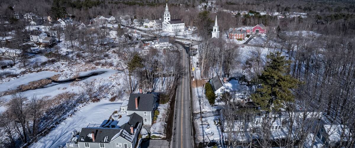 A snow-covered town with a prominent church and a mountain in the background.
