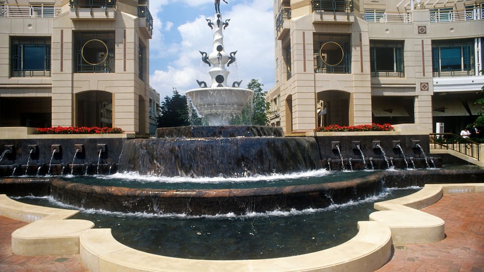 A multi-tiered fountain with water jets in front of a building with balconies and windows.