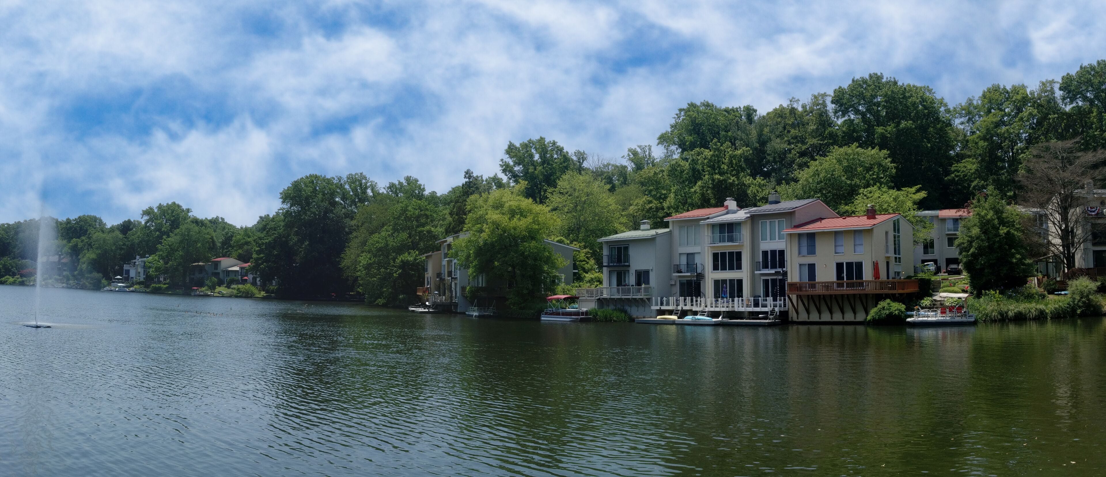 A lake with a fountain, surrounded by trees and buildings.