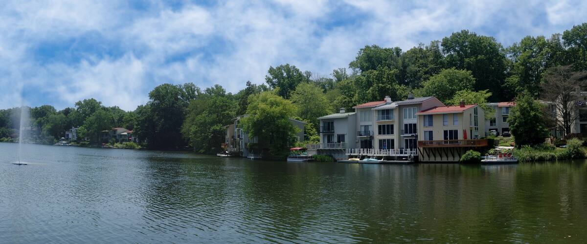 A lake with a fountain, surrounded by trees and buildings.