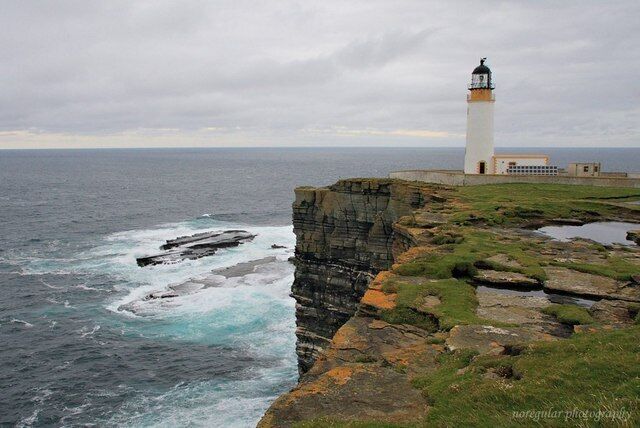 A lighthouse on a cliff by the sea.