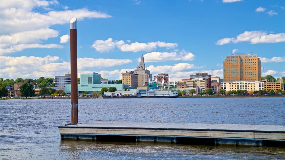 A waterfront cityscape with a prominent tall building, a historic clock tower, and a modern glass building.