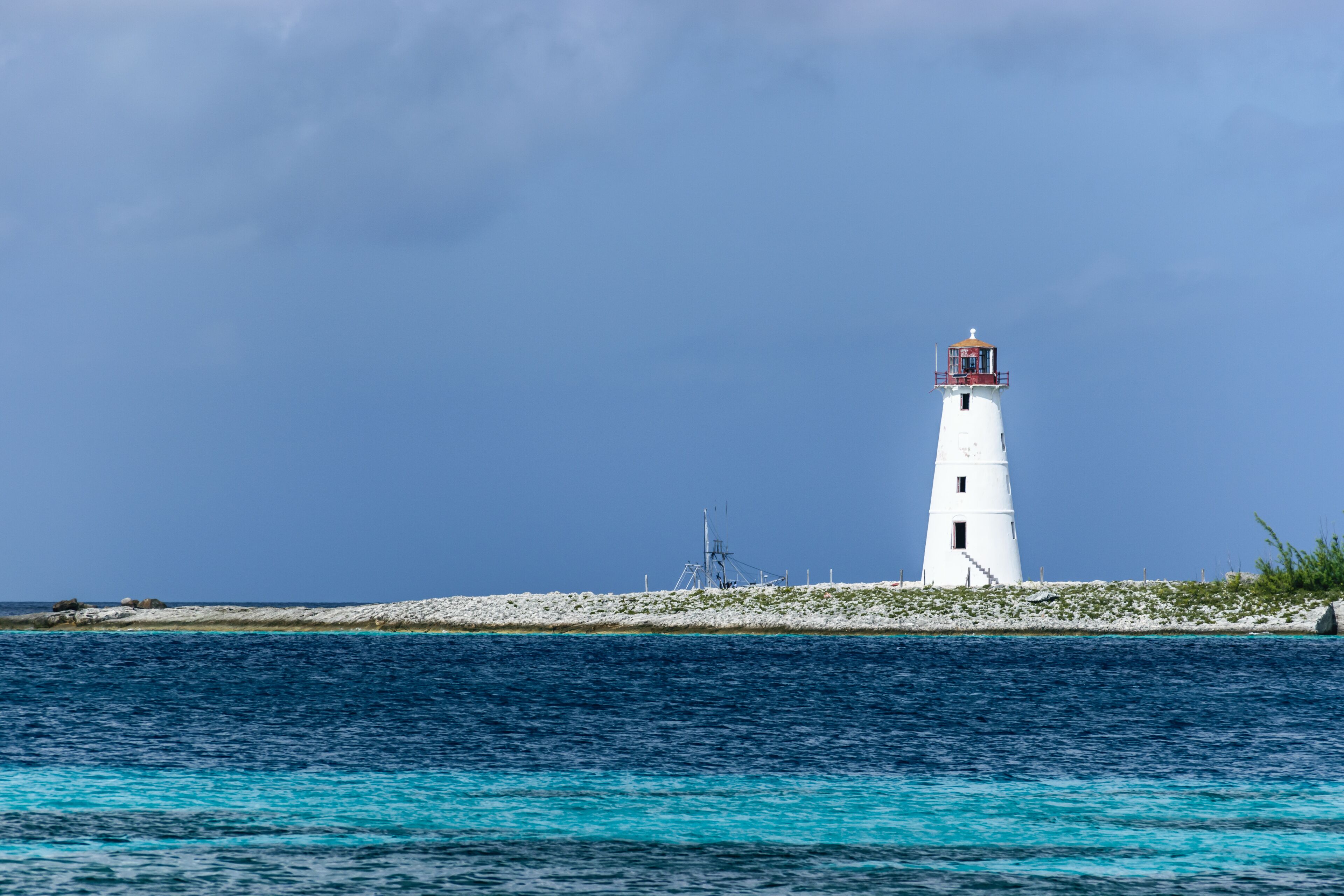 Un faro blanco en una pequeña isla con aguas azul turquesa.