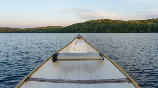 Canoe in a lake surrounded by mountains at sunset.