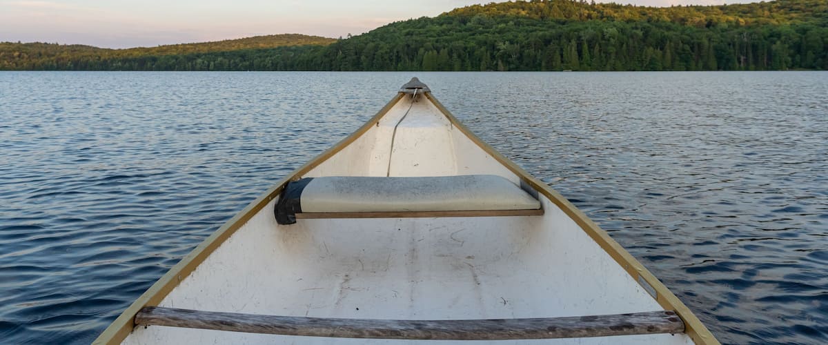 Canoe in a lake surrounded by mountains at sunset.