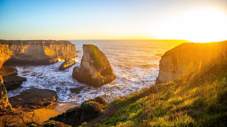 A coastal landscape with prominent rock formations and a clear sky.