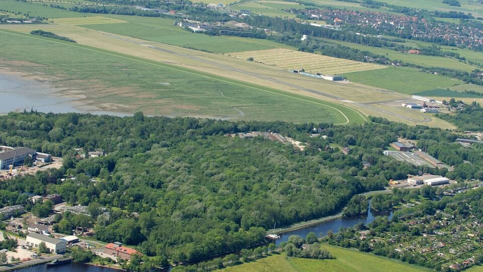 A river winding through a town surrounded by green fields and forests.