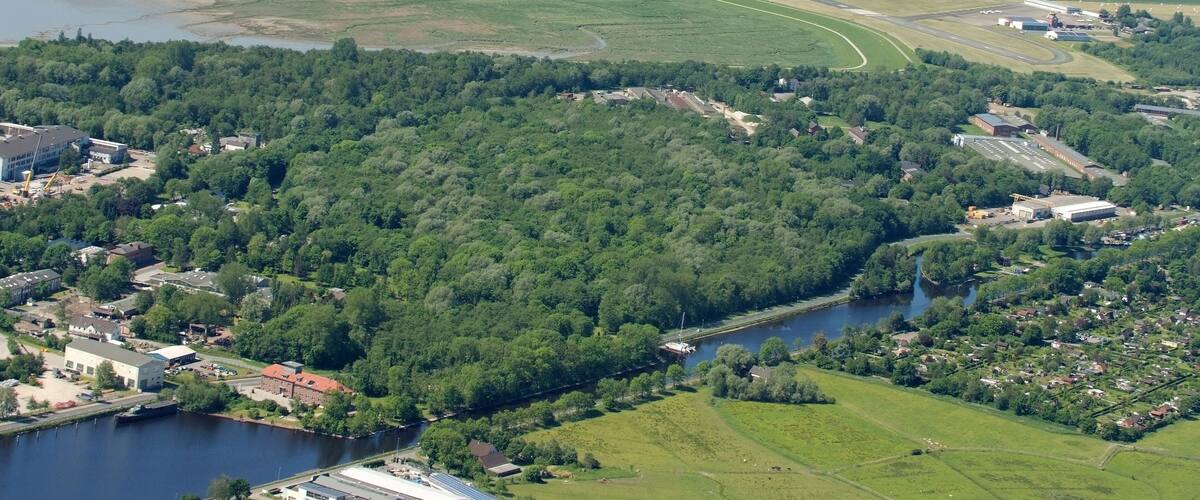 A river winding through a town surrounded by green fields and forests.