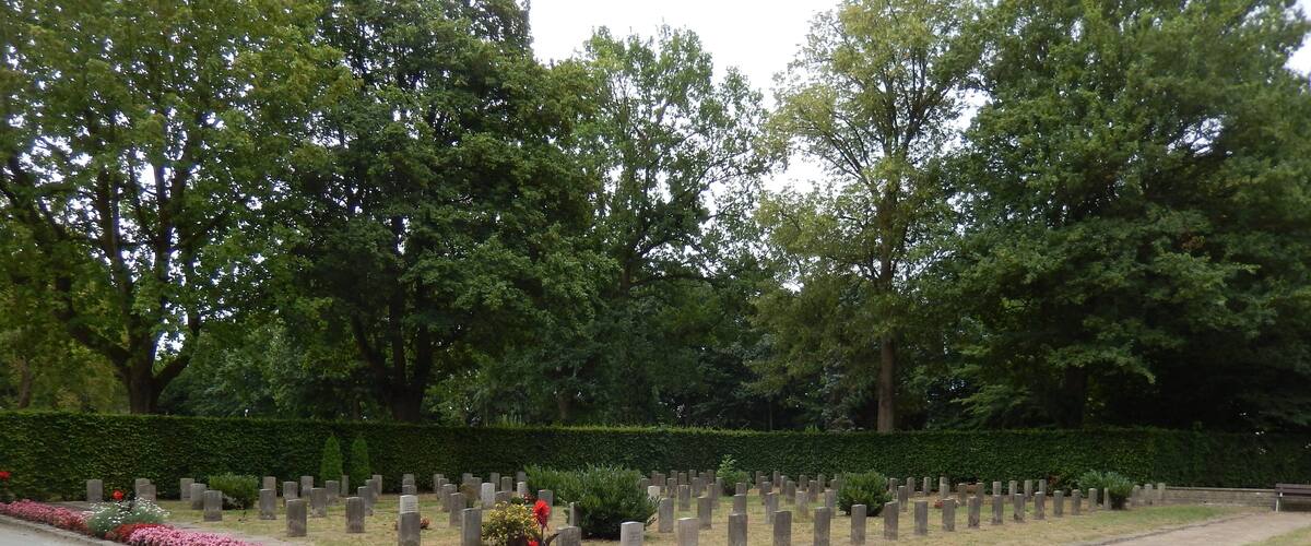 A cemetery with numerous headstones and a pathway.