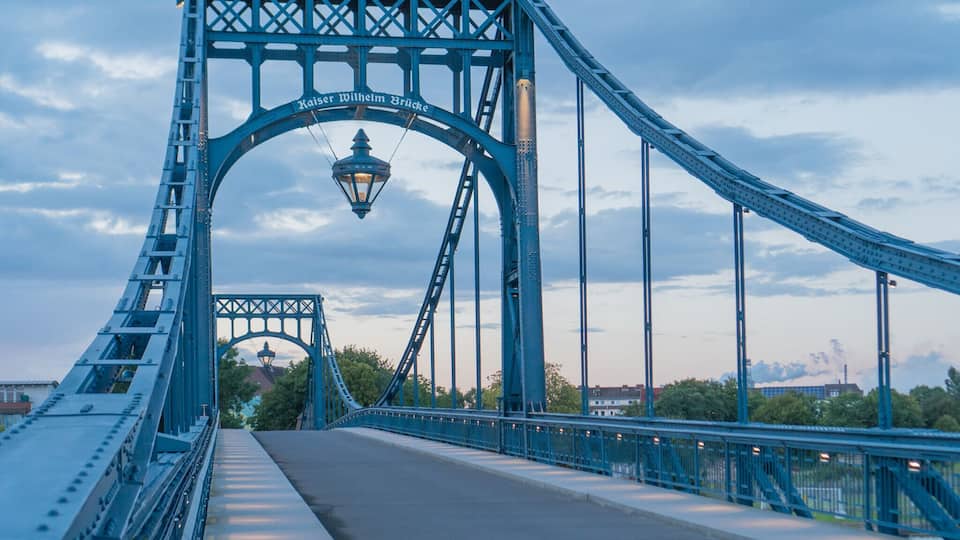 A blue bridge with a street lamp and the text "Kaiser Wilhelm Bridge" on it.