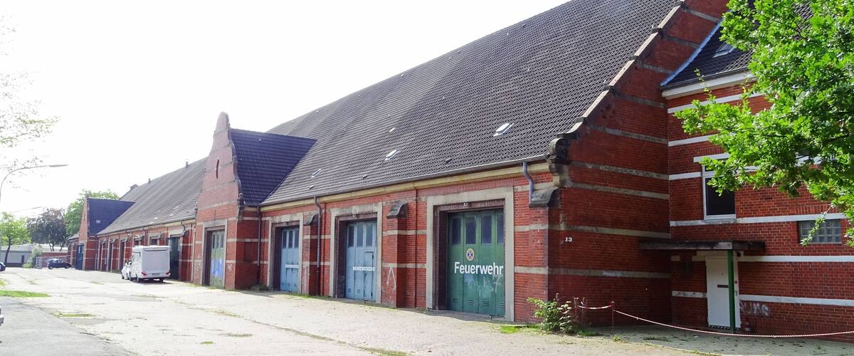 A row of red brick buildings with green doors, one labeled "Feuerwehr".