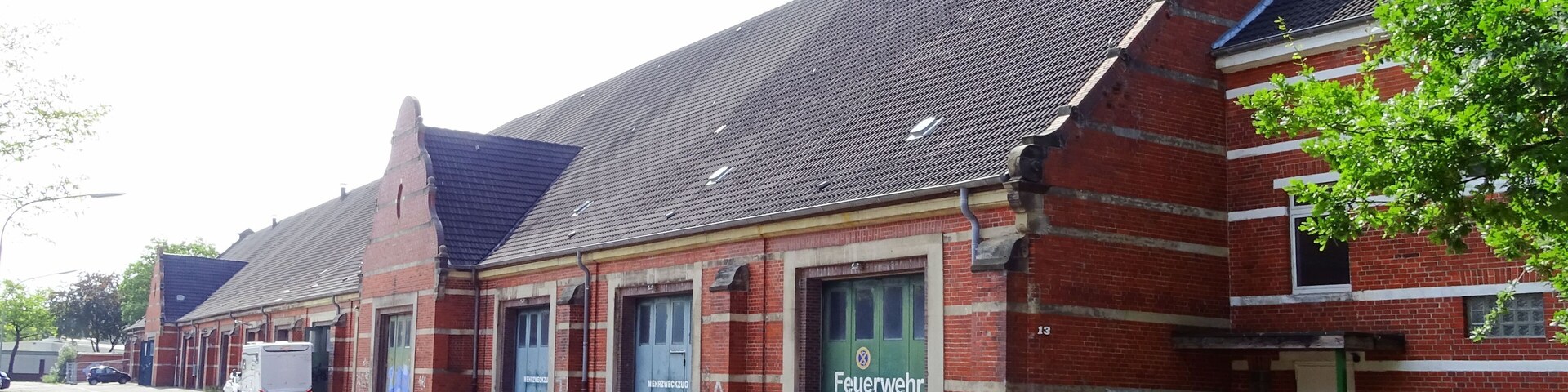 A row of red brick buildings with green doors, one labeled "Feuerwehr".