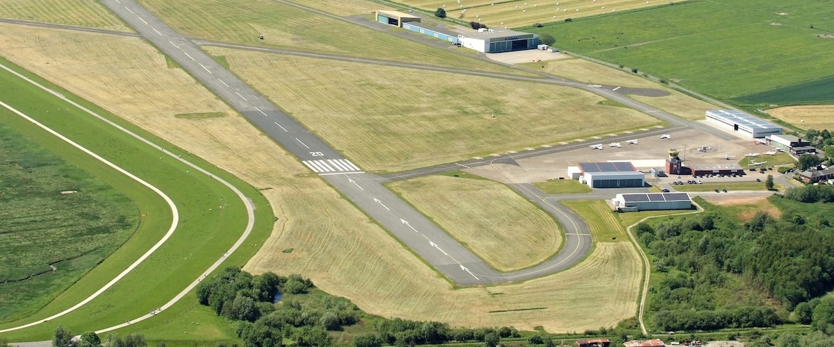 An airport runway with adjacent fields and buildings.