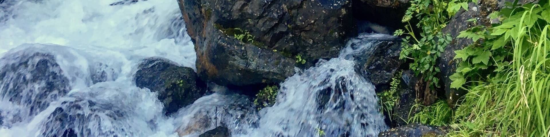 One of Palmer, Alaska's best kept secrets, this waterfall is visible from the parking area... if you can find that. Driving along the Old Glenn Highway, you will turn onto the Knik River Road, next to the Knik River Bridge. Maybe a mile down the road, look for a handmade sign that says Pioneer Falls. It can be tricky to spot! The gravel parking area is the very next right. You can see the waterfall from there, and it's only a short walk in to get close up. Just watch out for the cow parsnip. The toxins in the plant can leave bare skin with awful blisters!