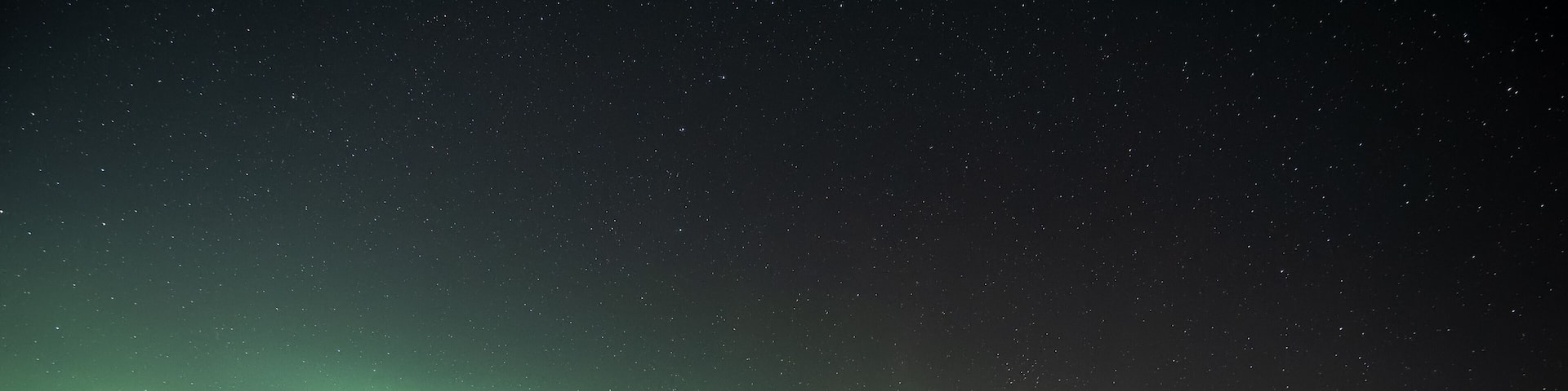 A night sky with the aurora borealis over snow-covered mountains and a frozen landscape.