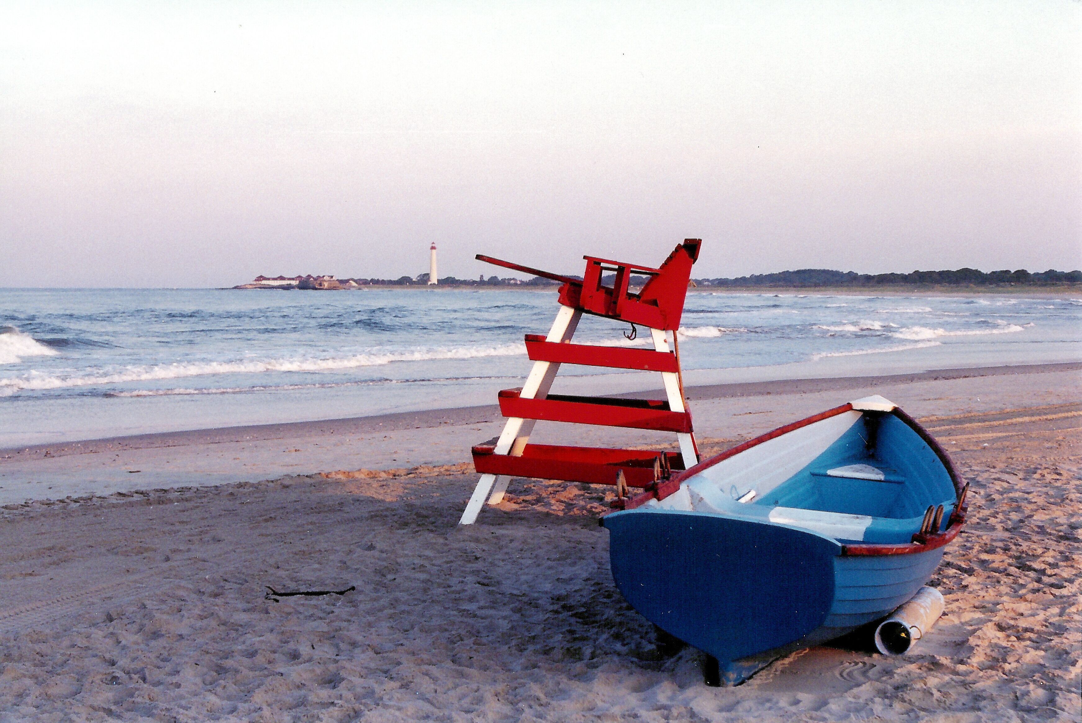 A beach with a blue boat and a red lifeguard stand.