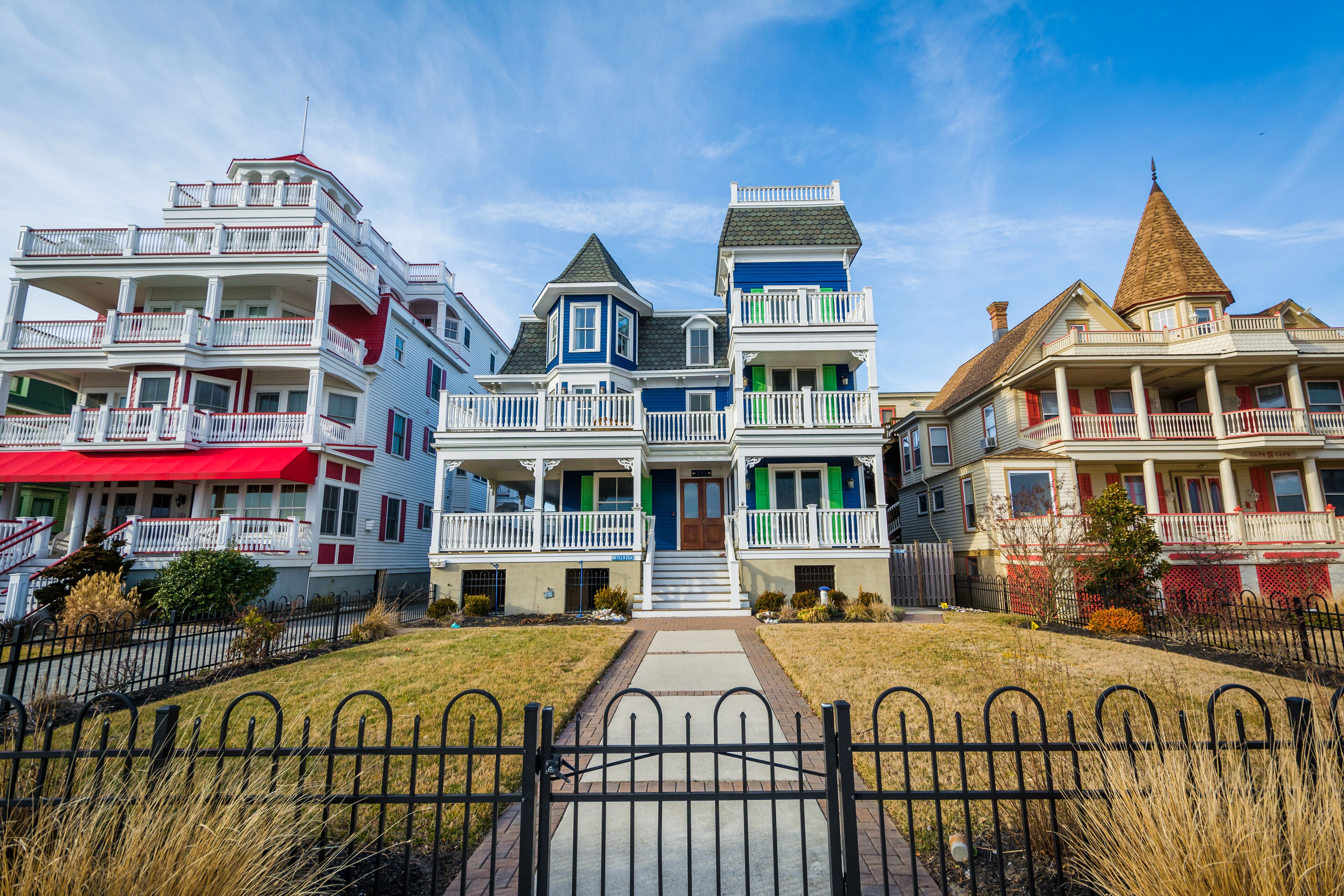 A row of colorful Victorian-style houses with multiple stories, balconies, and a well-maintained lawn.