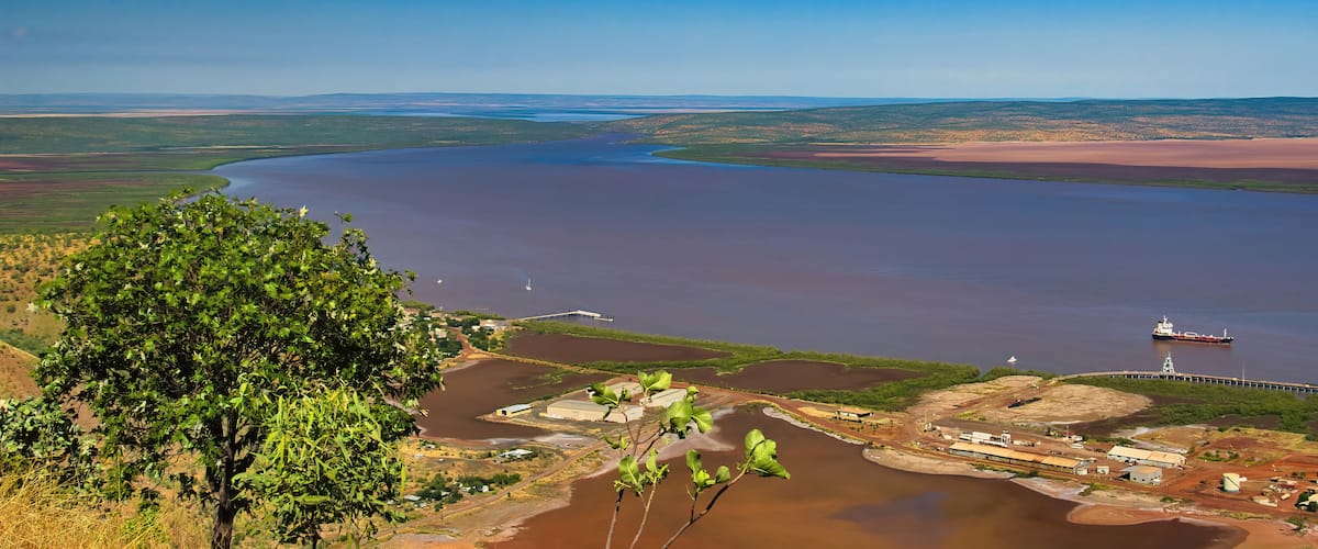 A river meandering through a landscape with a bridge, a ship, and industrial buildings.