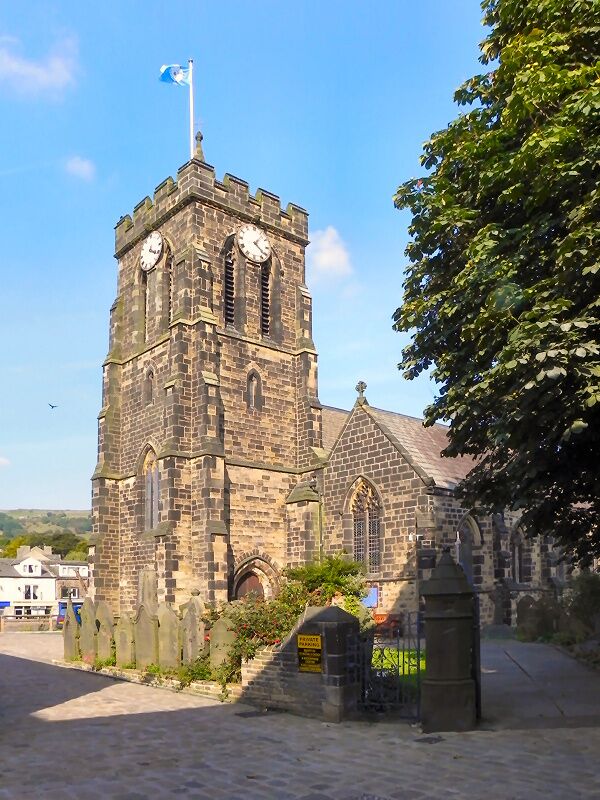 A historic stone church with a clock tower, a flag, and a gate.