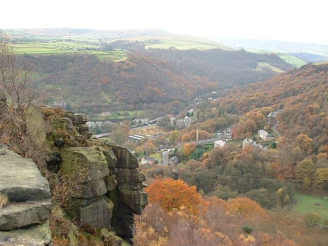 A valley with a town nestled among hills, a rocky outcrop in the foreground, and autumn-colored trees.