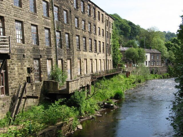 A river flowing alongside a historic brick building with a bridge.