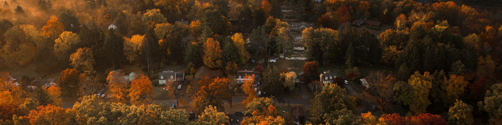 A misty autumn landscape with a valley, scattered houses, and distant hills.