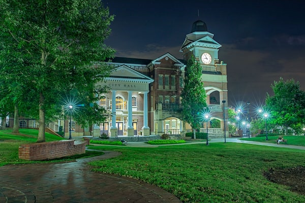 Small town parks just outside the big city are a great way to spend a Friday evening unwinding from the weekly stresses. A couple sit together enjoying the relaxing atmosphere while engaged in conversation. They huddle together as the warm day relinquishes its grasp to a cool evening.
