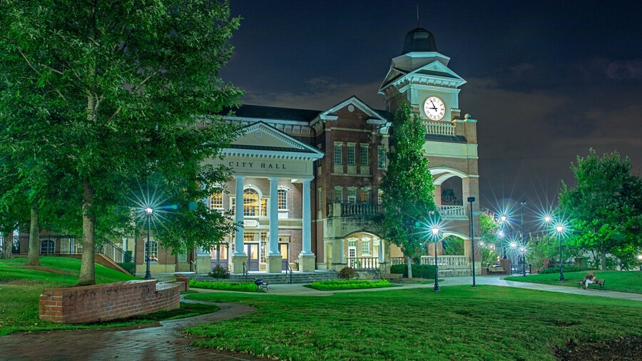 Small town parks just outside the big city are a great way to spend a Friday evening unwinding from the weekly stresses. A couple sit together enjoying the relaxing atmosphere while engaged in conversation. They huddle together as the warm day relinquishes its grasp to a cool evening.