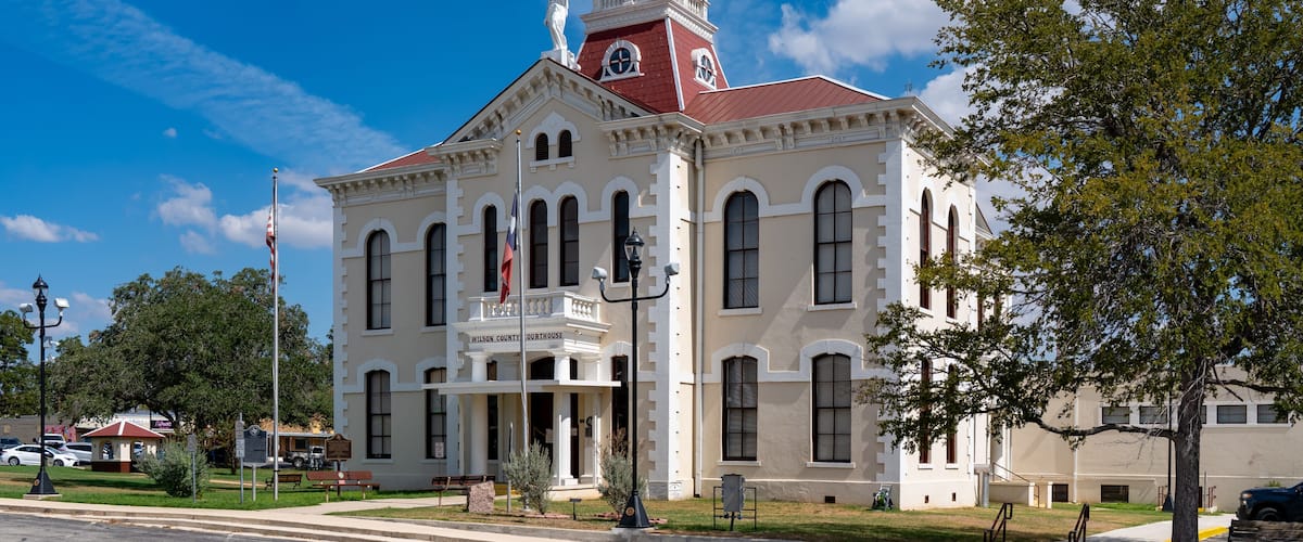 A historic courthouse with a prominent clock tower, surrounded by a well-maintained lawn and a clear blue sky.