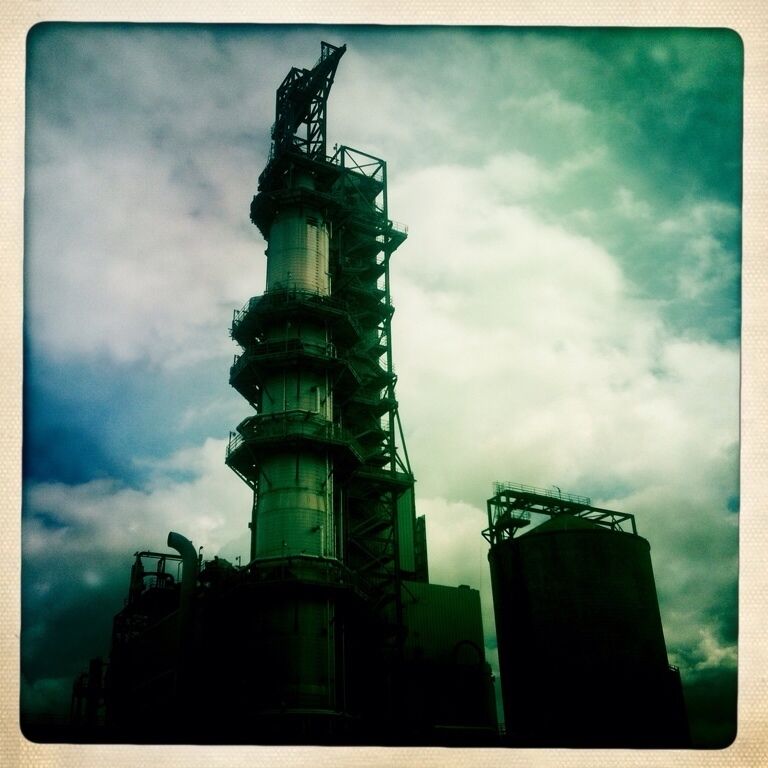 A large industrial tower with multiple levels and a complex framework, set against a cloudy sky.