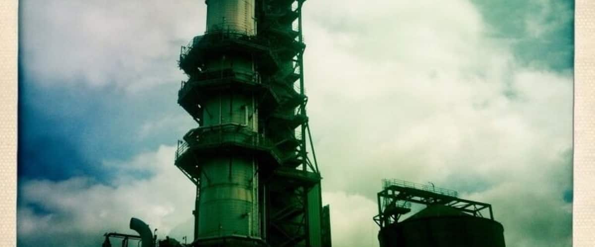 A large industrial tower with multiple levels and a complex framework, set against a cloudy sky.
