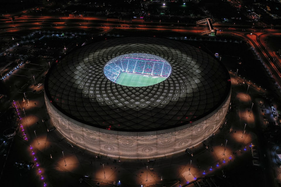 Un estadio grande con techo de cúpula distintiva y carreteras circundantes, de noche.