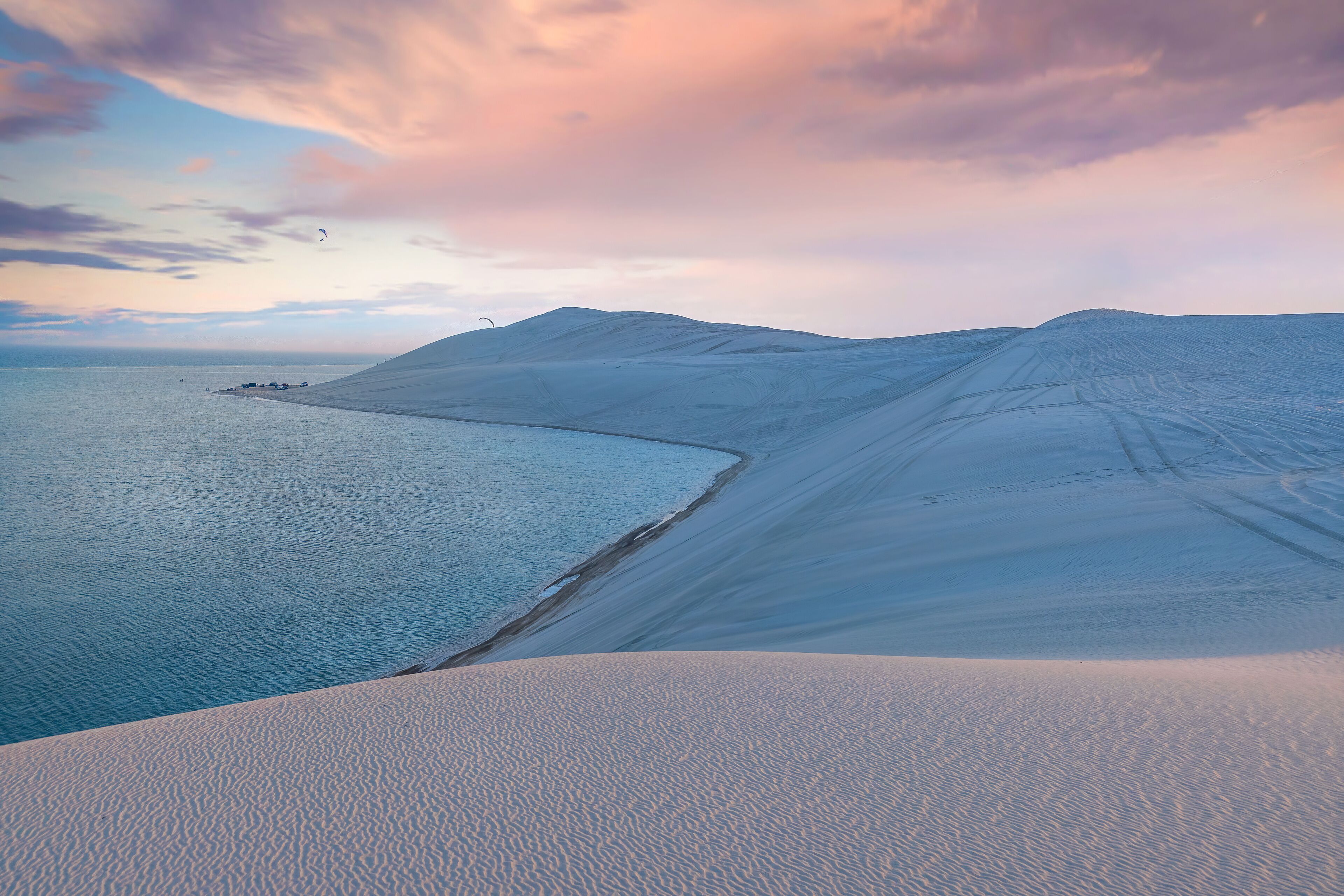 A vast desert landscape with sand dunes and a coastline.