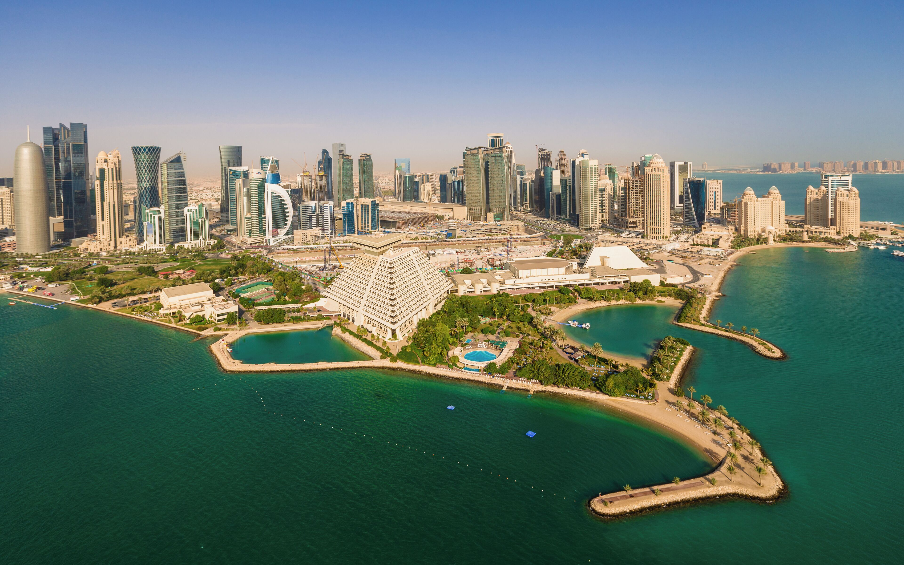 A coastal cityscape with modern skyscrapers and a marina.
