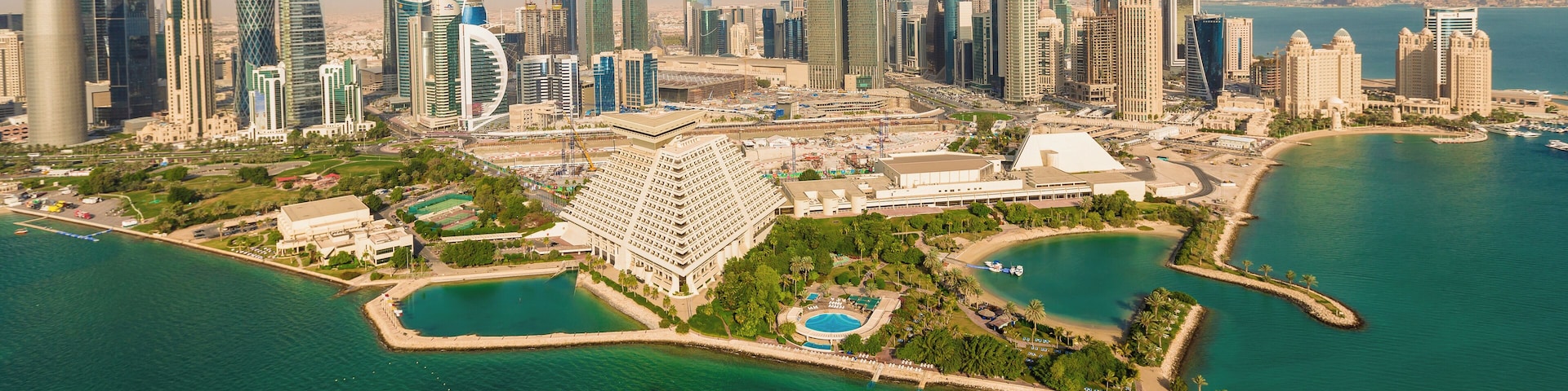 A coastal cityscape with modern skyscrapers and a marina.