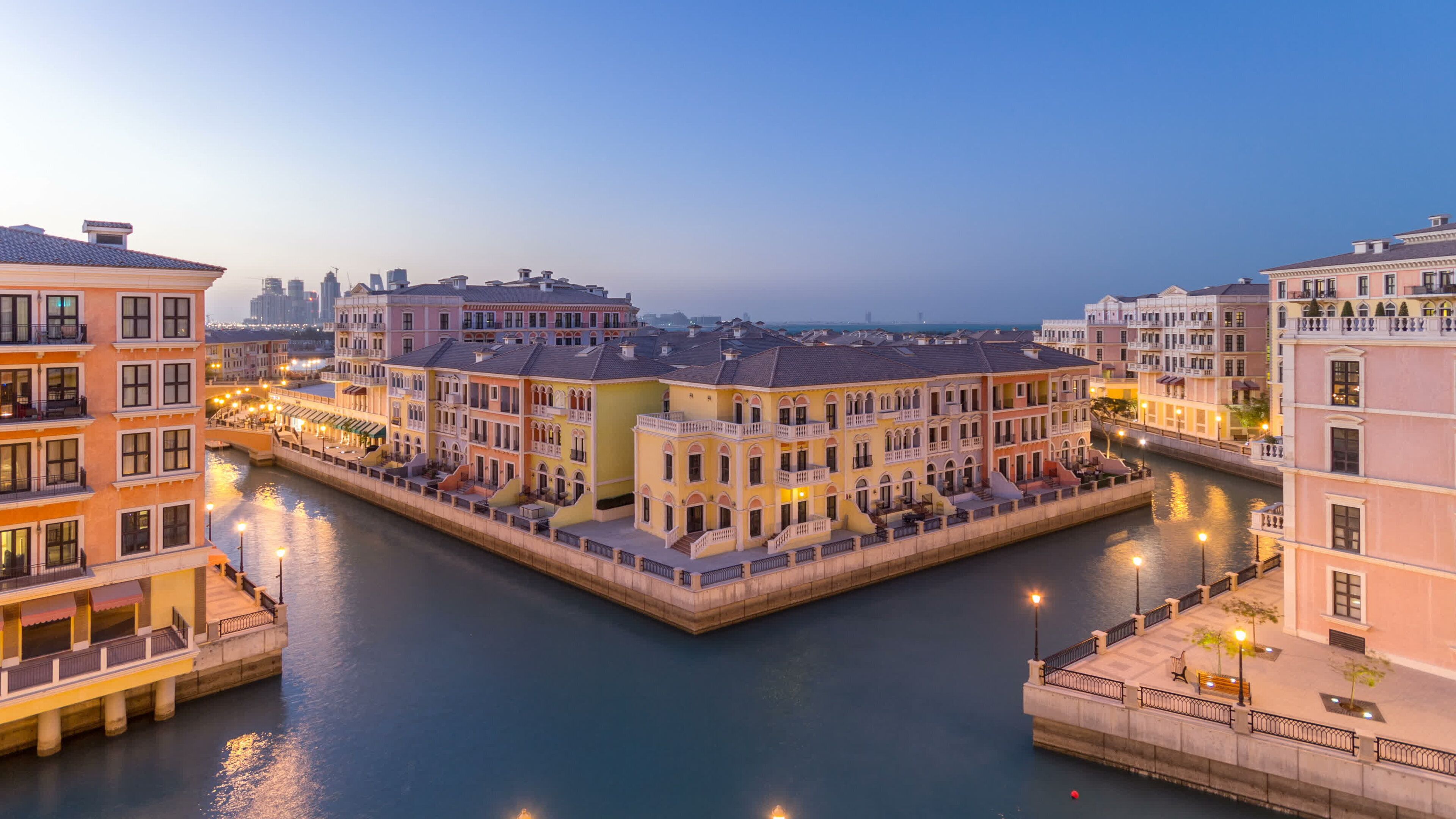 A canal with buildings on both sides, a bridge, and a city skyline in the background.