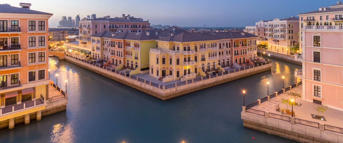A canal with buildings on both sides, a bridge, and a city skyline in the background.