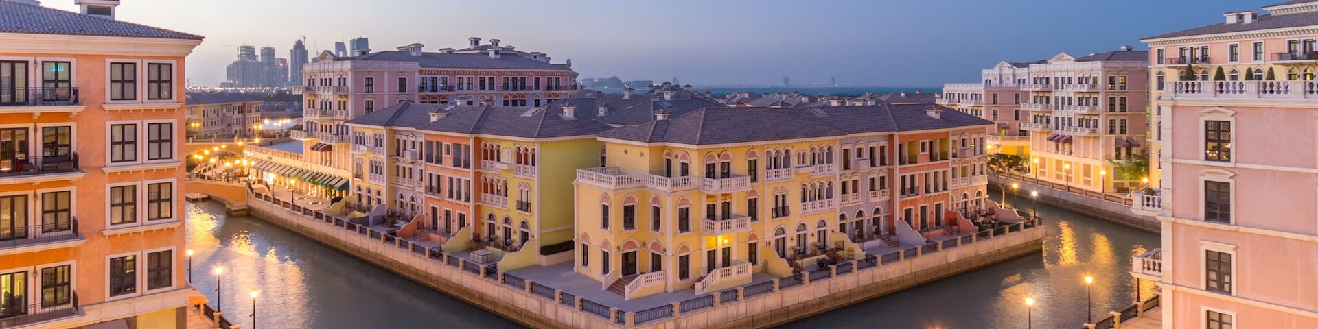 A canal with buildings on both sides, a bridge, and a city skyline in the background.
