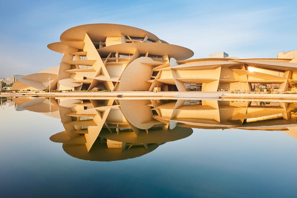 Un edificio de arquitectura moderna con un diseño orgánico y distintivo, reflejado en aguas tranquilas.