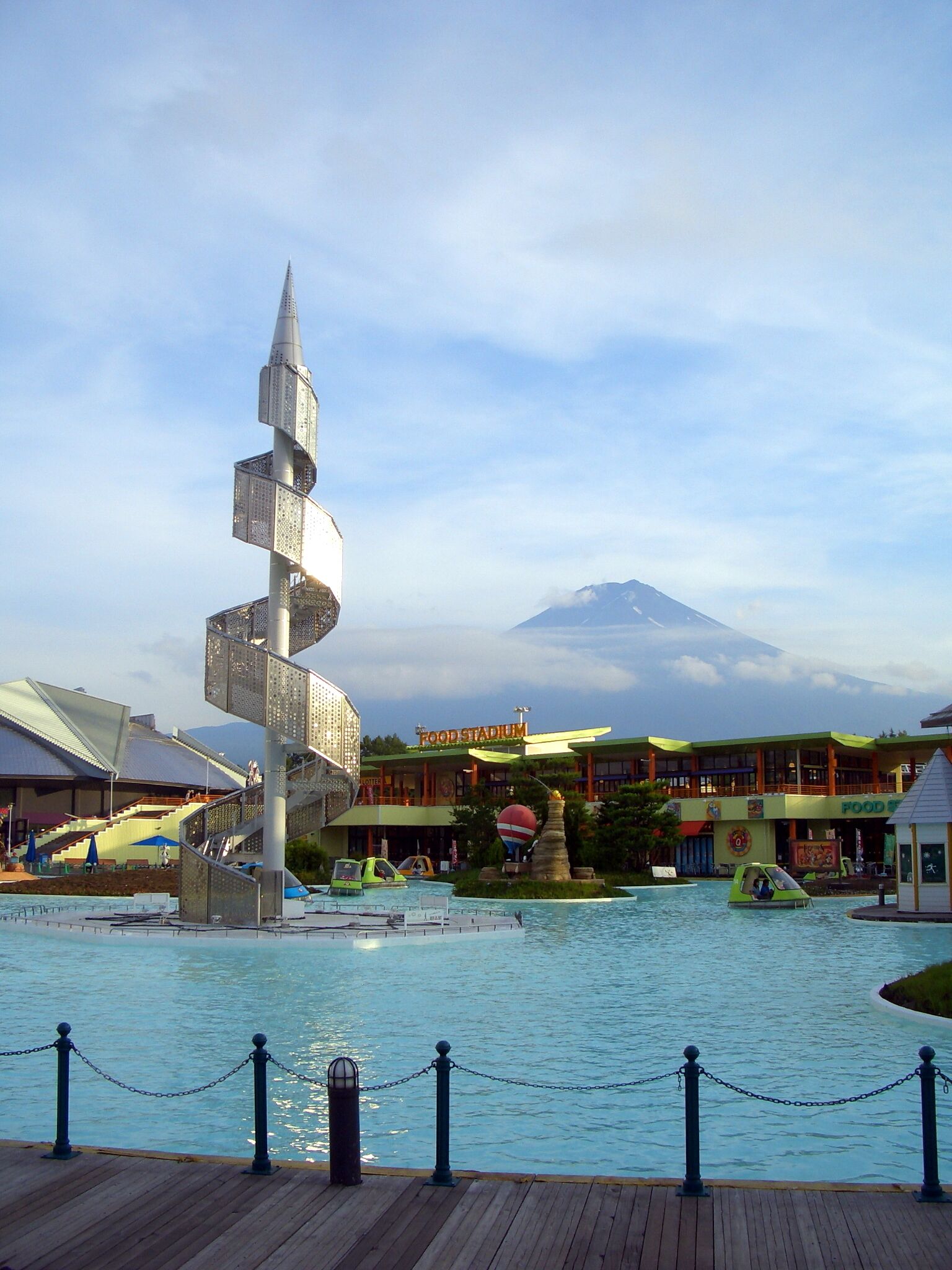Una fuente en espiral, un espacio gastronómico y una montaña al fondo.