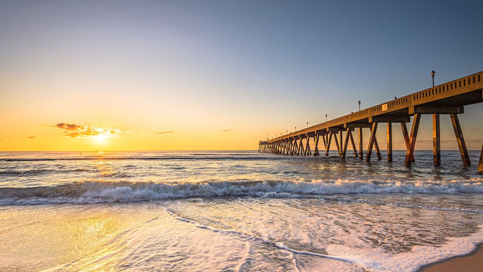 A pier extending into the ocean at sunset.