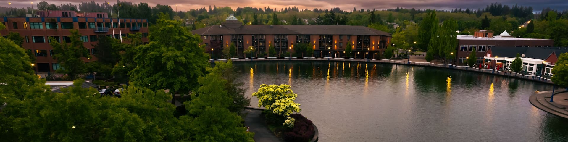 A riverside view with a bridge, buildings, and lush greenery.