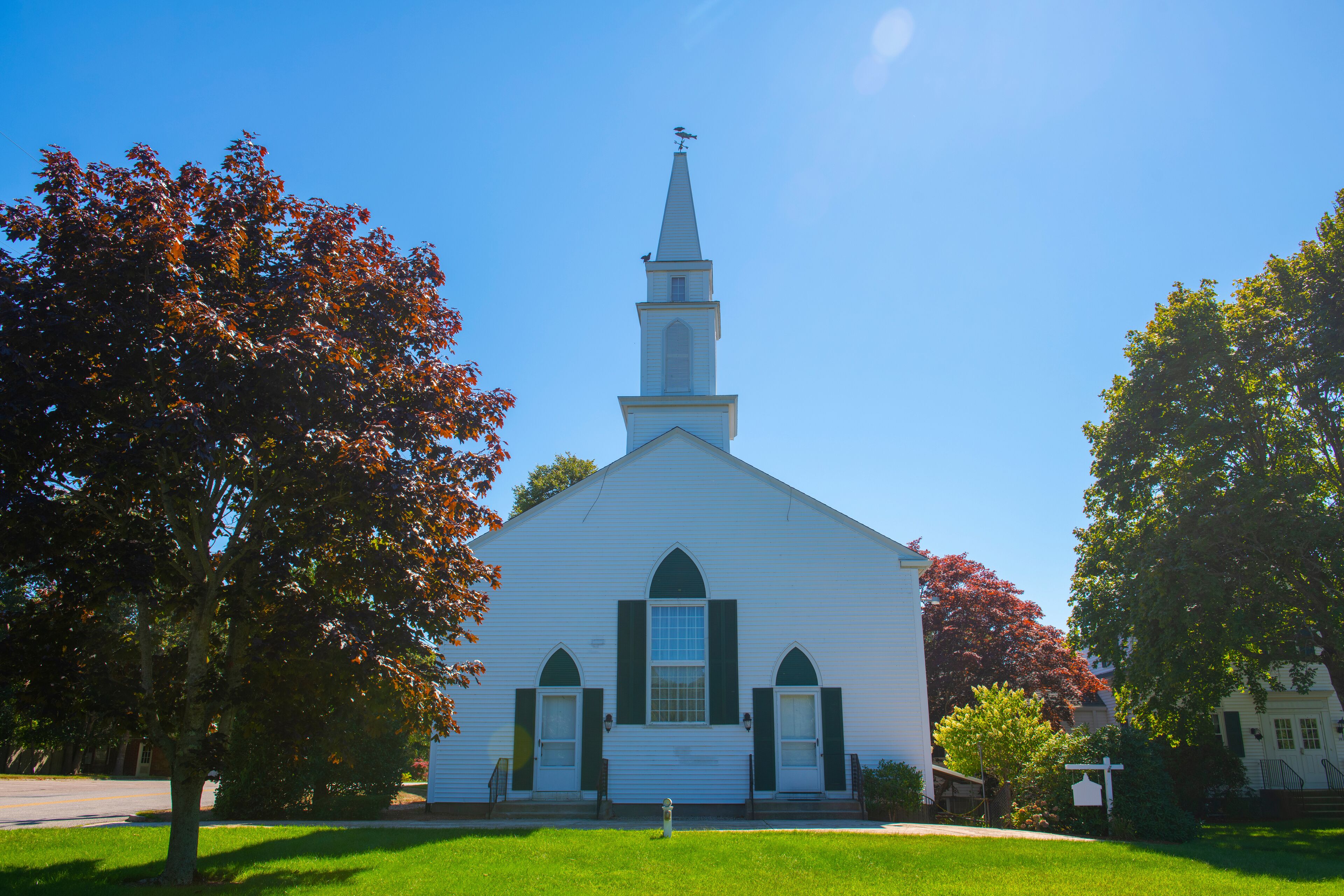 A white church with a steeple and arched windows.